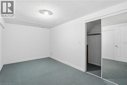 Unfurnished bedroom featuring a closet, dark colored carpet, and a textured ceiling - 513 Rexford Drive, Hamilton, ON - Indoor Photo Showing Other Room