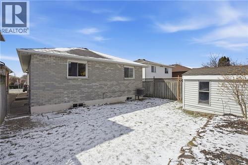 Snow covered rear of property with brick siding, a fenced backyard, an outdoor structure, and a gate - 513 Rexford Drive, Hamilton, ON - Outdoor