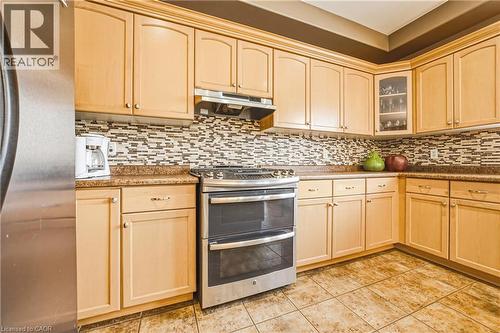 Kitchen featuring stainless steel appliances, light wood finish cabinets, glass insert cabinets, and light tile patterned floors - 120 Valiant Circle, Hamilton, ON - Indoor Photo Showing Kitchen