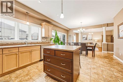 Kitchen with a center island, tasteful backsplash, decorative columns, dishwasher, and light tile patterned floors - 120 Valiant Circle, Hamilton, ON - Indoor Photo Showing Kitchen With Double Sink