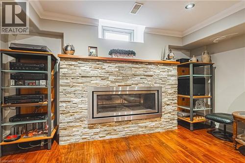 Living area featuring crown molding, wood finished floors, and a stone fireplace - 120 Valiant Circle, Hamilton, ON - Indoor With Fireplace