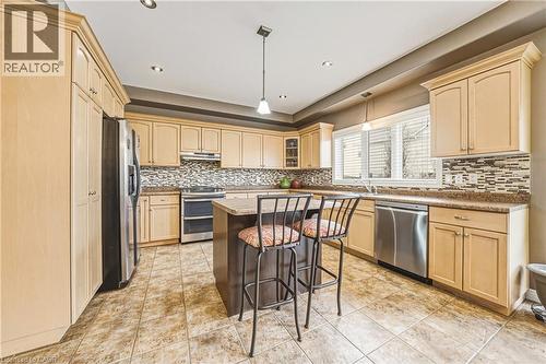 Kitchen featuring stainless steel appliances, a kitchen bar, a kitchen island, glass insert cabinets, and light wood finish cabinetry - 120 Valiant Circle, Hamilton, ON - Indoor Photo Showing Kitchen