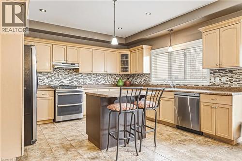 Kitchen with stainless steel appliances, glass insert cabinets, a breakfast bar area, pendant lighting, and a kitchen island - 120 Valiant Circle, Hamilton, ON - Indoor Photo Showing Kitchen