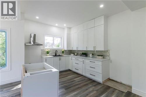 Kitchen with white cabinets, backsplash, dark wood-type flooring, and recessed lighting - 1411 E 56 Highway, Glanbrook, ON - Indoor Photo Showing Laundry Room