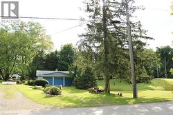 View of front of home featuring a front lawn, driveway, and view of wooded area - 
