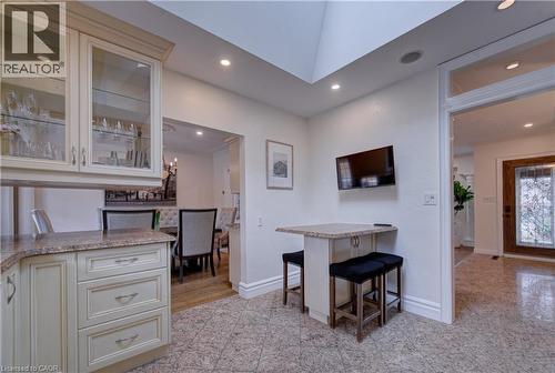 Kitchen with glass fronted cabinets, a breakfast bar area, recessed lighting, cream cabinets, and light stone countertops - 655 Ellengale Road, Burlington, ON - Indoor