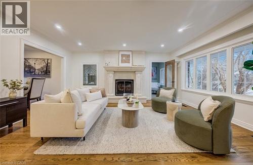 Living area with ornamental molding, wood finished floors, recessed lighting, and a large fireplace - 655 Ellengale Road, Burlington, ON - Indoor Photo Showing Living Room With Fireplace