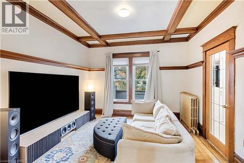 Living room featuring beam ceiling, coffered ceiling, radiator heating unit, wood finished floors, and crown molding - 134 Sherman Avenue S, Hamilton, ON - Indoor Photo Showing Living Room