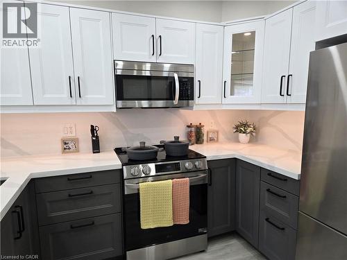 Two tone kitchen with two tone cabinetry, stainless steel appliances, glass fronted cabinets, and light stone countertops - 59 Highgate Road Unit# 1, Kitchener, ON - Indoor Photo Showing Kitchen With Upgraded Kitchen