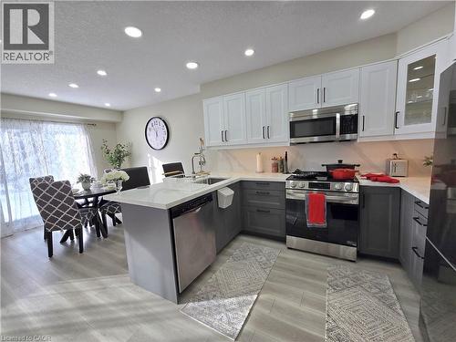 Dual tone kitchen with two tone cabinets, a peninsula, stainless steel appliances, a textured ceiling, and recessed lighting - 59 Highgate Road Unit# 1, Kitchener, ON - Indoor Photo Showing Kitchen