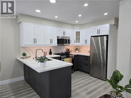 Dual tone kitchen featuring stainless steel appliances, dual tone cabinets, a peninsula, light wood finished floors, and recessed lighting - 59 Highgate Road Unit# 1, Kitchener, ON - Indoor Photo Showing Kitchen With Upgraded Kitchen