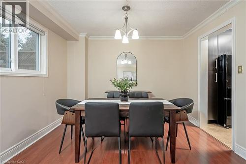 Dining area featuring a chandelier, crown molding, wood finished floors, and a textured ceiling - 1278 Consort Crescent, Burlington, ON - Indoor Photo Showing Dining Room