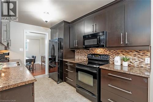 Kitchen with black appliances, tasteful backsplash, and dark wood finish cabinetry - 1278 Consort Crescent, Burlington, ON - Indoor Photo Showing Kitchen With Double Sink