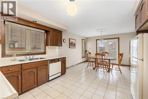 Kitchen featuring white appliances, light countertops, decorative light fixtures, light tile patterned floors, and tasteful backsplash - 57 Derek Drive, Hamilton, ON - Indoor