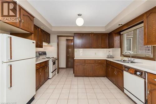 Kitchen featuring white appliances, light countertops, light tile patterned floors, recessed lighting, and tasteful backsplash - 57 Derek Drive, Hamilton, ON - Indoor Photo Showing Kitchen With Double Sink