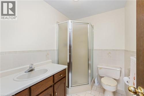 Full bath featuring light tile patterned flooring, a shower stall, vanity, tile walls, and wainscoting - 57 Derek Drive, Hamilton, ON - Indoor Photo Showing Bathroom