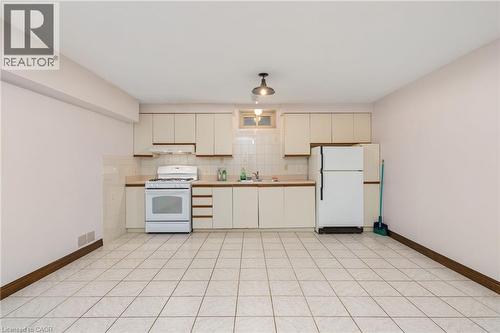 Kitchen featuring white appliances, cream cabinetry, light countertops, and tasteful backsplash - 57 Derek Drive, Hamilton, ON - Indoor Photo Showing Kitchen