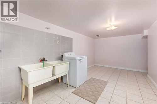 Laundry area featuring washer / dryer, tile walls, and light tile patterned floors - 57 Derek Drive, Hamilton, ON - Indoor Photo Showing Laundry Room