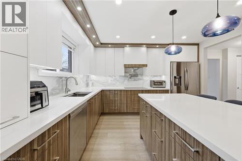 Dual tone kitchen with modern cabinets, two tone cabinets, stainless steel appliances, pendant lighting, and backsplash - 273 Bryant Crescent, Burlington, ON - Indoor Photo Showing Kitchen With Upgraded Kitchen