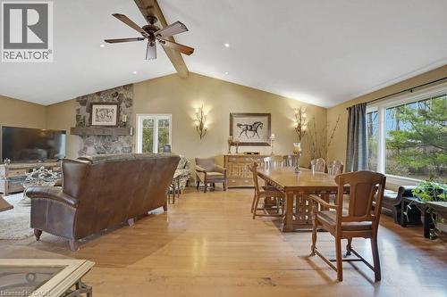Dining room featuring light wood-type flooring, a ceiling fan, beamed ceiling, and a stone fireplace - 5511 Second Line, Erin, ON - Indoor