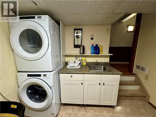 Laundry area with stacked washer / dryer, cabinet space, and light tile patterned floors - 86 Devonglen Drive, Kitchener, ON - Indoor Photo Showing Laundry Room