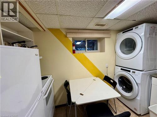 Laundry area with stacked washing machine and dryer, a drop ceiling, and tile patterned floors - 86 Devonglen Drive, Kitchener, ON - Indoor Photo Showing Laundry Room