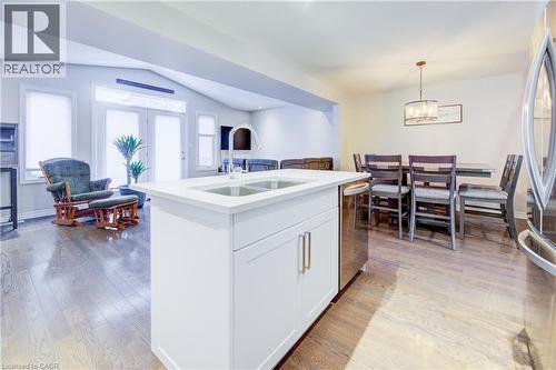Kitchen with open floor plan, white cabinets, vaulted ceiling, decorative light fixtures, and a kitchen island with sink - 34 Harrison Street, Stratford, ON - Indoor