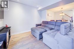 Living room featuring light wood-type flooring, a chandelier, stairway, and recessed lighting - 