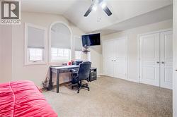 Bedroom with two closets, light carpet, vaulted ceiling, an office area, and ceiling fan - 