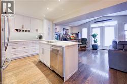 Kitchen with open floor plan, white cabinetry, appliances with stainless steel finishes, vaulted ceiling, and recessed lighting - 