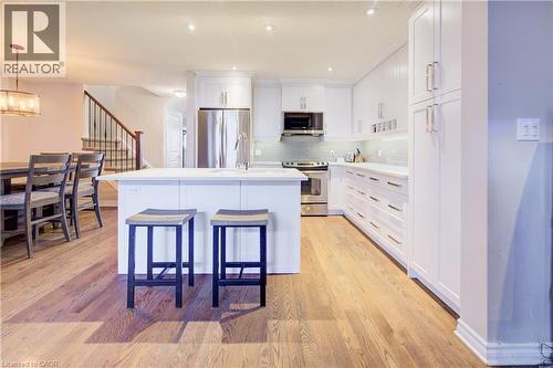 Kitchen featuring white cabinets, appliances with stainless steel finishes, a kitchen island with sink, and light wood finished floors - 34 Harrison Street, Stratford, ON - Indoor Photo Showing Kitchen With Upgraded Kitchen