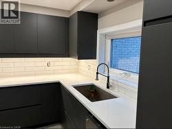 Kitchen with light stone counters, dark cabinets, modern cabinets, and freestanding refrigerator - 