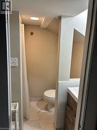 Bathroom with curtained shower, vanity, and lofted ceiling - 