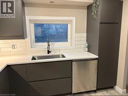 Kitchen featuring tasteful backsplash, appliances with stainless steel finishes, gray cabinetry, and light wood-style floors - 