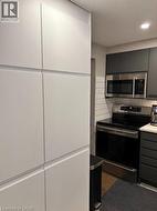 Kitchen with appliances with stainless steel finishes, gray cabinetry, and light countertops - 