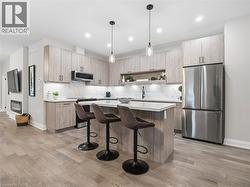 Kitchen with stainless steel appliances, light wood finish cabinets, a center island, a breakfast bar, and pendant lighting - 