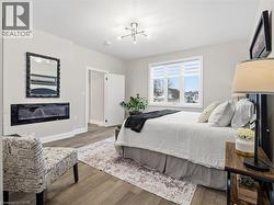 Bedroom with wood finished floors and a glass covered fireplace - 