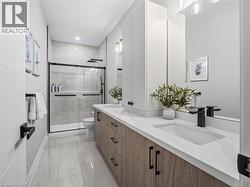 Full bathroom featuring double vanity, a shower stall, light marble finish floors, and recessed lighting - 