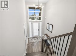 Foyer entrance with a high ceiling, wood finished floors, and suspended lighting - 