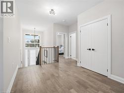 Corridor with an upstairs landing, light wood finished floors, and hanging lights - 