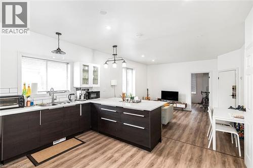 Kitchen with a peninsula, open floor plan, glass insert cabinets, pendant lighting, and dark wood finish cabinets - 57 New Street, Hamilton, ON - Indoor Photo Showing Kitchen With Double Sink