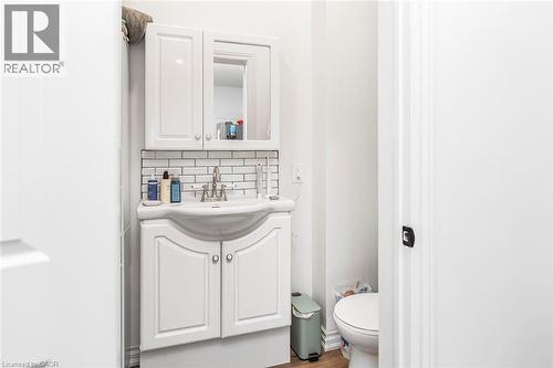 Half bath with vanity, wood finished floors, and decorative backsplash - 57 New Street, Hamilton, ON - Indoor Photo Showing Bathroom