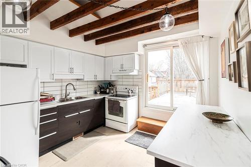 Two tone kitchen featuring white appliances, two tone cabinets, light countertops, decorative backsplash, and beam ceiling - 57 New Street, Hamilton, ON - Indoor Photo Showing Kitchen With Double Sink