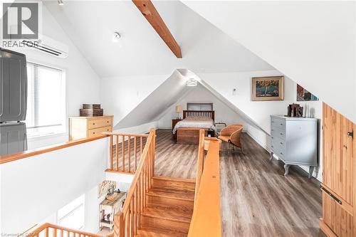 Bedroom with wood finished floors, vaulted ceiling with beams, and stacked washer / dryer - 57 New Street, Hamilton, ON - Indoor Photo Showing Other Room