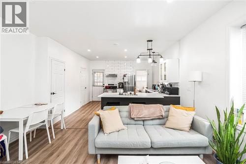Living area featuring light wood-style floors and hanging lights - 57 New Street, Hamilton, ON - Indoor Photo Showing Living Room