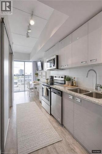 Kitchen with stainless steel appliances, light stone counters, light wood-style flooring, modern cabinets, and dual tone cabinetry - 257 Hemlock Street Unit# 607, Waterloo, ON - Indoor Photo Showing Kitchen With Stainless Steel Kitchen With Double Sink