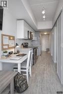 Kitchen with stainless steel appliances, a peninsula, a kitchen bar, light wood finished floors, and light stone counters - 