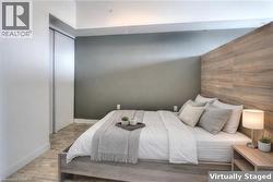 Bedroom with an accent wall, wood walls, wood finished floors, and a closet - 