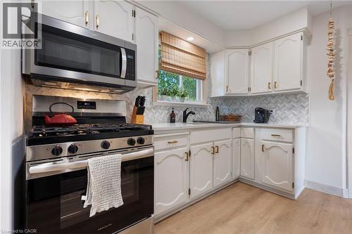 Kitchen with stainless steel appliances, white cabinets, light wood-style floors, and light countertops - 181 Cedar Drive, Turkey Point, ON - Indoor Photo Showing Kitchen