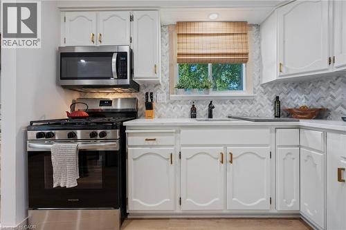 Kitchen with appliances with stainless steel finishes, white cabinets, light countertops, and decorative backsplash - 181 Cedar Drive, Turkey Point, ON - Indoor Photo Showing Kitchen